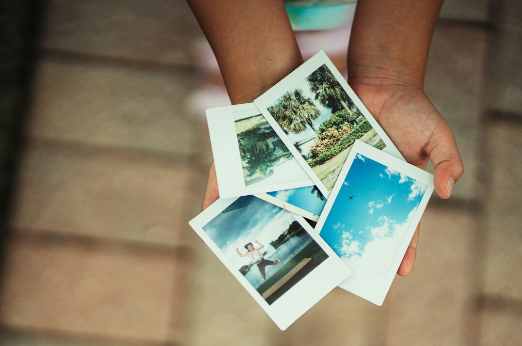 Hands sorting through printed photographs on a light table