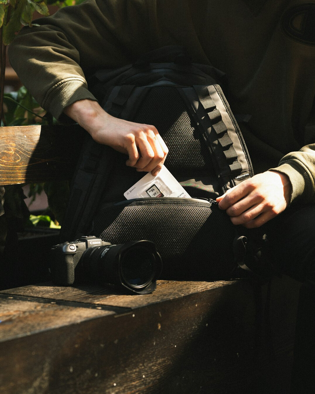 Person writing field notes in a notebook beside a camera outdoors